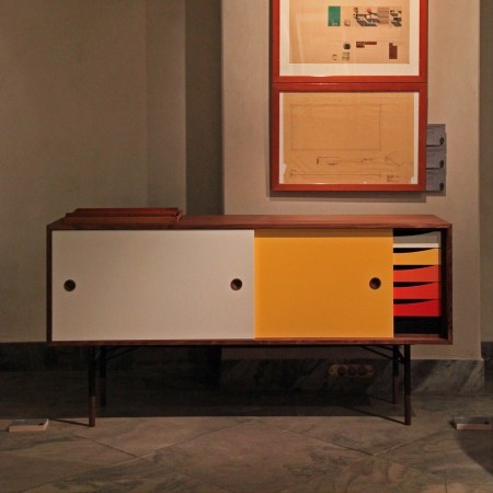 Finn Juhl was preoccupied with shapes and colors during his life because of his great interest in cubist and surrealistic art. The Finn Juhl Sideboard with colored sliding doors and trays was designed in 1955. It is part of a series of cubist wood cabinets that float on delicate steel frames with wood  "feet".