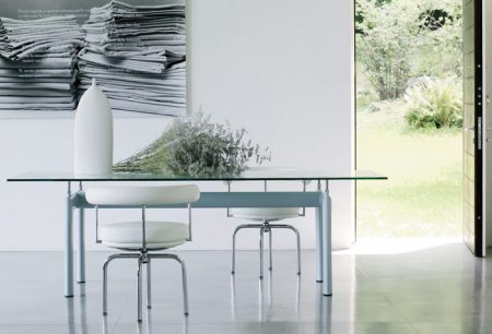 The table is available with semi gloss grey, light blue, green, mud, ivory or black enameled steel base. The base has four supporting points with steel threaded shanks, permitting height adjustment. The top is available in crystal or textured glass, natural oak, black-stained oak or American walnut and a selection of sizes. 