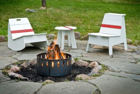 The complete group includes a Lounge, Rocker, and Side Car Table all styled with convenient handles and a sporty stripe. The Lounge is designed for numerous sitting positions either down low or up top in the bleacher position. The bleacher seat also doubles as a standing height table. The Rocker is wider and lower and sets the driver in a perfect balance of bodily comfort and mental relaxation. The Side Car table ties the collection together and will help make pit stops last as long as necessary. Both the Lounge and Rocker have an open storage trunk in the back for outdoor accessories. Beneath the top shelf on the Lounge is installed a stainless steel bottle opener for quick bottle changes. Helmet and suit not included. Made in Duluth, MN, USA.